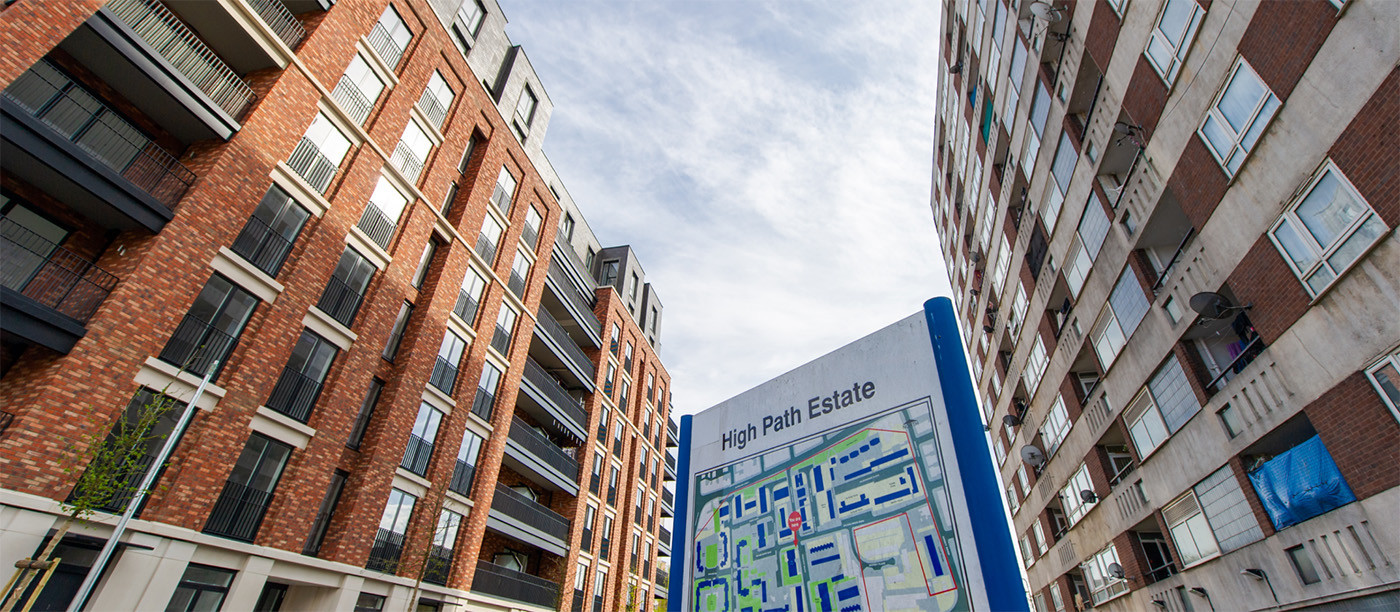 A new build block of flats opposite an older block, with a High Path estate plan sign in the foreground